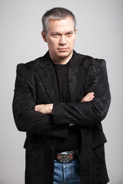 Портрет взрослого мужчины в черной куртке, держащегося за руки
 - Фото, изображение
