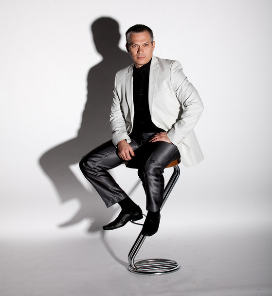 Man in suit sitting on bar chair against white background - Fotografie, Obrázek