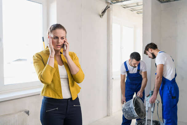 Foremen are renovating a room, a customer speaks on the phone - Photo, Image