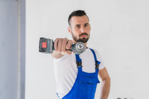 Bearded man shows a drill to the camera - Photo, Image