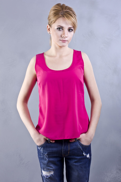 Beautiful young blond woman in a bright pink blouse on a gray background - Φωτογραφία, εικόνα