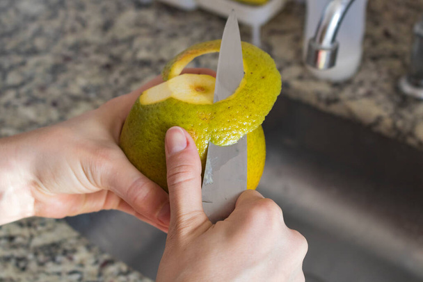 Image de concept de fruit - Les mains féminines coupent l'orange dans la cuisine - Photo, image