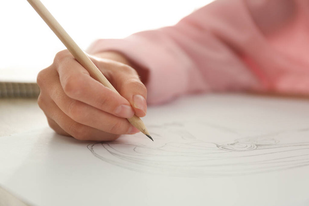 Woman drawing girl's portrait with pencil on sheet of paper at table, closeup - Photo, image
