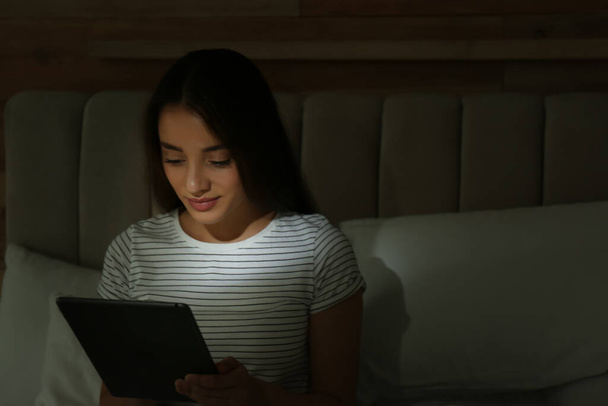 Happy woman using tablet in dark bedroom - Foto, Bild