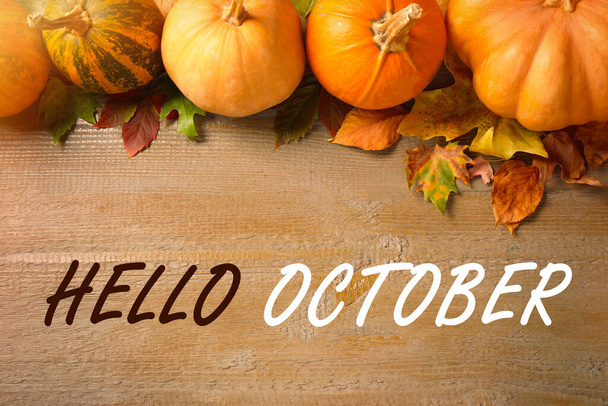 Hello October text, pumpkins and autumn leaves on wooden background, flat lay - Photo, Image