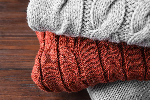 Stack of folded warm sweaters on wooden background, closeup - Valokuva, kuva