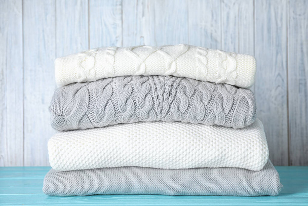 Stack of folded warm sweaters on turquoise wooden table - Foto, Imagen
