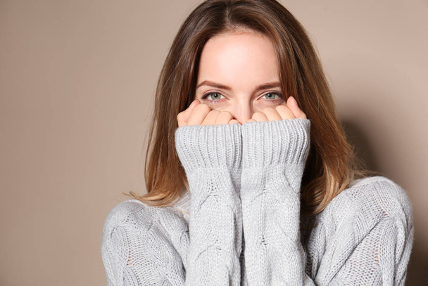 Pretty young woman wearing warm sweater on beige background  - Foto, immagini