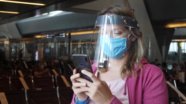 Mujer con máscara médica y protector facial en el aeropuerto - Metraje, vídeo