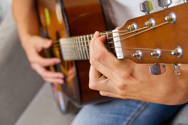 Jonge jongen die gitaar speelt. Close-up van de hand van de man die klassieke gitaar speelt. tiener leren gitaar spelen. - Foto, afbeelding