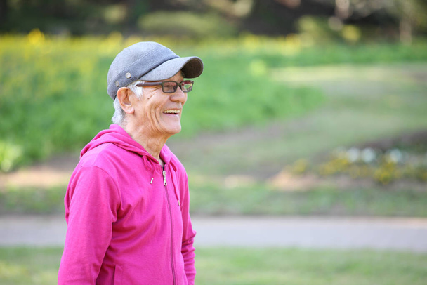  senior Japanese man in pink wear smiles outdoor - Φωτογραφία, εικόνα