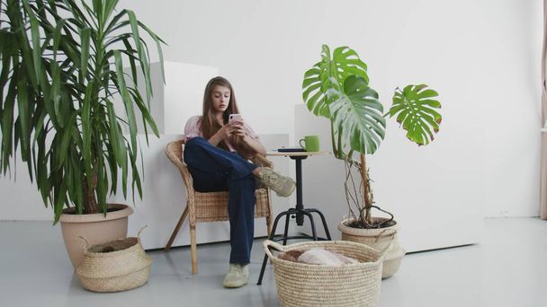 Attraktive junge Frau nutzt Telefon Social Media Plattform und sitzen auf Stuhl zu Hause bleiben zu Hause entspannen mobile Couch Technologie weibliche Nachricht Innenraum - Foto, Bild