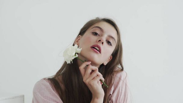Atractiva hermosa modelo de mujer joven con flores mirando y posando en la cámara - Foto, imagen