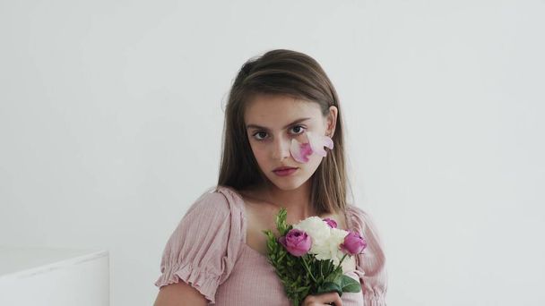 Profesjonalna młoda kobieta model z kwiatami patrząc i pozowanie przed kamerą - Zdjęcie, obraz
