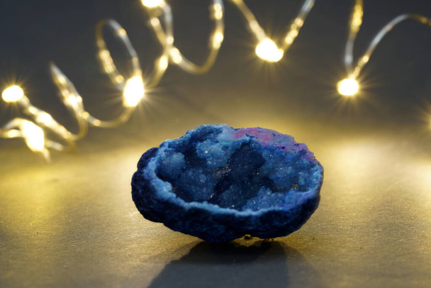 A closeup shot of a purple rock with string lights in the background - Photo, Image