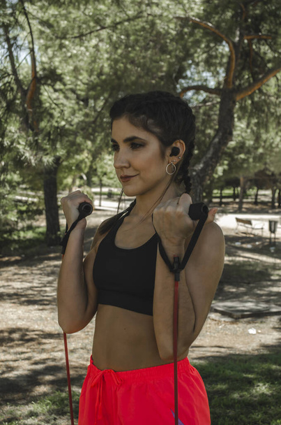 A vertical shot of a Hispanic young female working out outdoors - Photo, image