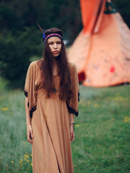 Retrato de belleza de una joven indígena morena en vestido tradicional, posa en bosque salvaje en verano, día soleado, aislado sobre un fondo de hierba verde. - Foto, Imagen
