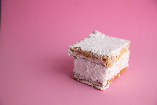 A selective focus closeup shot of a delicious pastel meringue with white filling on a pink background - Fotoğraf, Görsel