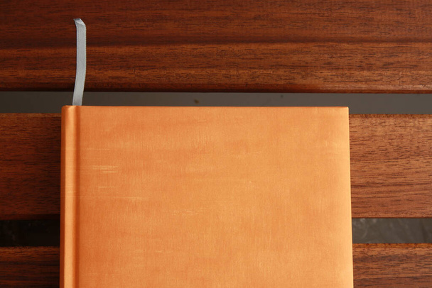 Крупный план книги с оранжевой обложкой на красочном фоне - Фото, изображение