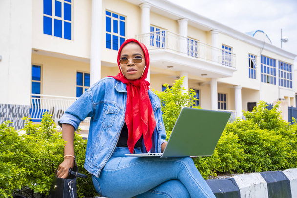 Eine junge Afrikanerin sitzt mit ihrem Laptop in einem Park - Foto, Bild