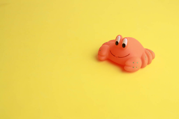 An isolated shot of a small cute crab bathtub toy on a yellow surface - Foto, immagini
