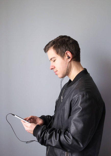 A Young man using smartphone listening to music wearing headphones - Valokuva, kuva