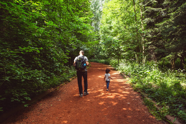 Father carrying a backpack and son holding a stick walking together on a path in the woods, Belgrad Forest, Istanbul, Turkey - Photo, Image