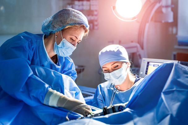 Medical team performing surgical operation in bright modern surgery room. Operating theatre. Modern equipment in clinic. Emergency room. - Foto, imagen