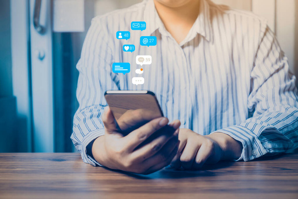 Pessoa usando um conceito de marketing de mídia social no telefone celular com ícones de notificação de como, mensagem, comentário e estrela acima da tela do smartphone. - Foto, Imagem