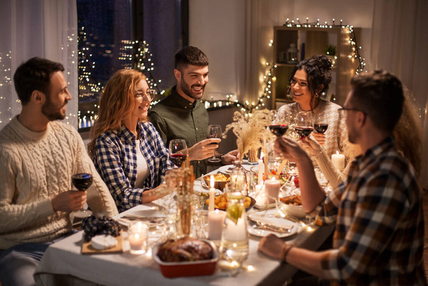 happy friends drinking red wine at christmas party - 写真・画像
