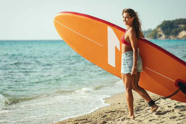 Gyönyörű fiatal női szörfös készül a szörfözésre.. - Fotó, kép