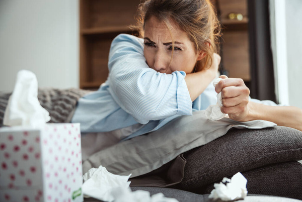 Jovem mulher está deitada doente em casa sofá tosse. - Foto, Imagem