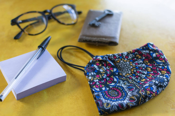 安全マスク、眼鏡、財布、キーと黄色のテーブルの上にペンでブロック - 写真・画像