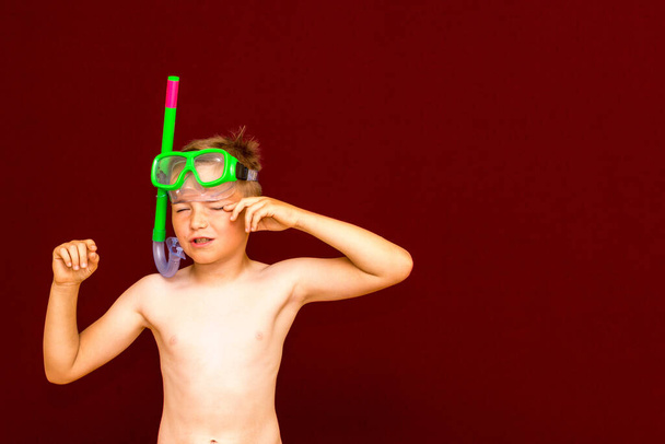 Poika sukeltamisen jälkeen mainostaa sukellus snorklaus naamio punaisella taustalla. Matkailu ja kesä käsite - Valokuva, kuva