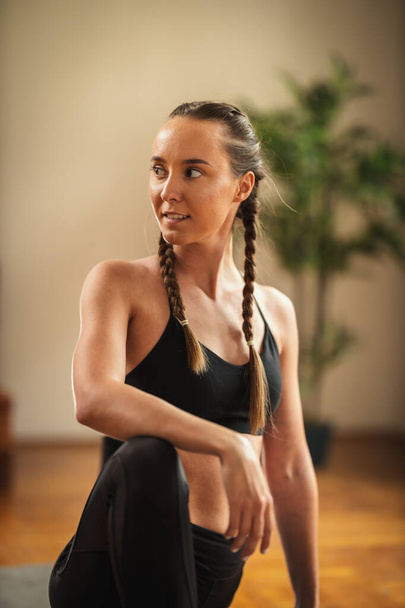 Beautiful fit young woman is doing stretching exercises in the apartment. - Zdjęcie, obraz