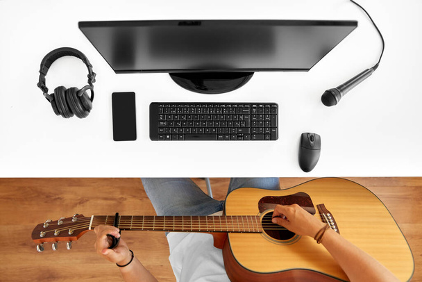 young man with computer playing guitar at table - Foto, imagen