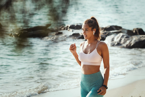 Kaunis nuori nainen valmistautuu tekemään venyttely liikuntaa meren rannalla kesällä aurinkoinen päivä. - Valokuva, kuva