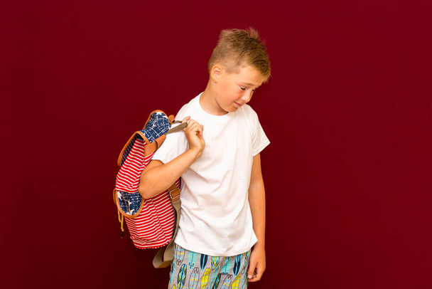 Niño de escuela cansado con mochila, aislado en la pared roja - Foto, Imagen