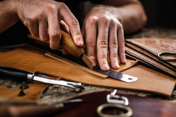 Detailní záběr obuvníka nebo řemeslných dělnických rukou. Kůže řemeslné nástroje na starém dřevěném stole. Dílna koženého řemesla. - Fotografie, Obrázek