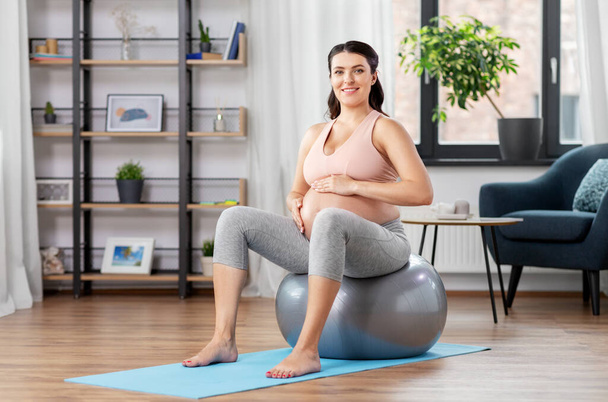pregnant woman exercising on fitness ball at home - Фото, зображення