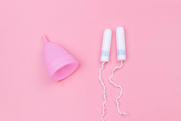 Pink reusable silicone menstrual cup and tampons on pink background. Top view. Concept of feminine hygiene, gynecology and health - Foto, Imagem