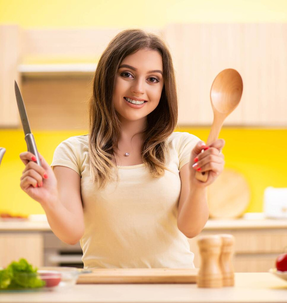 Νεαρή γυναίκα ετοιμάζει σαλάτα στο σπίτι στην κουζίνα - Φωτογραφία, εικόνα