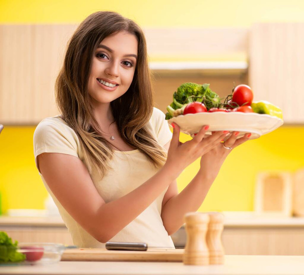 Junge Frau bereitet Salat zu Hause in Küche zu - Foto, Bild