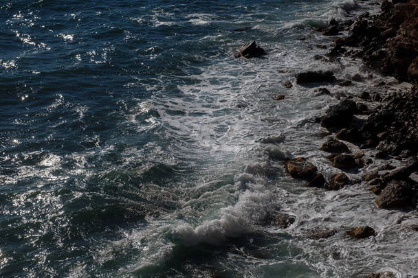 海の波の背景海の岩の海岸の荒波ターコイズブルーの水のグラデーションフォームを壊す。オープン海で大きな波。夏のモンスーン。波の白紋. - 写真・画像