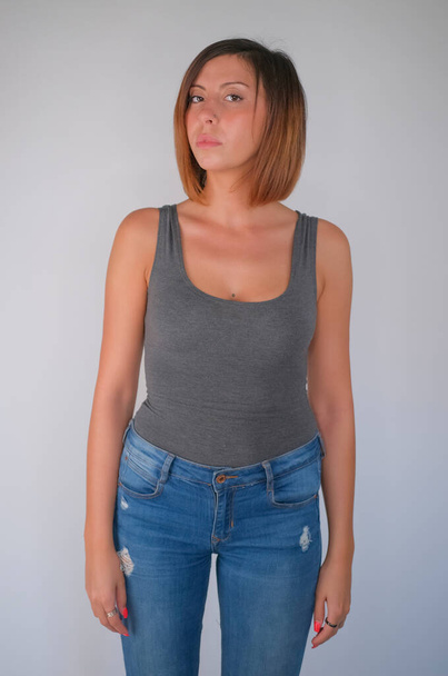 beautiful brunette girl with short hair gray top and jeans and high heels posing. High quality photo - Photo, image