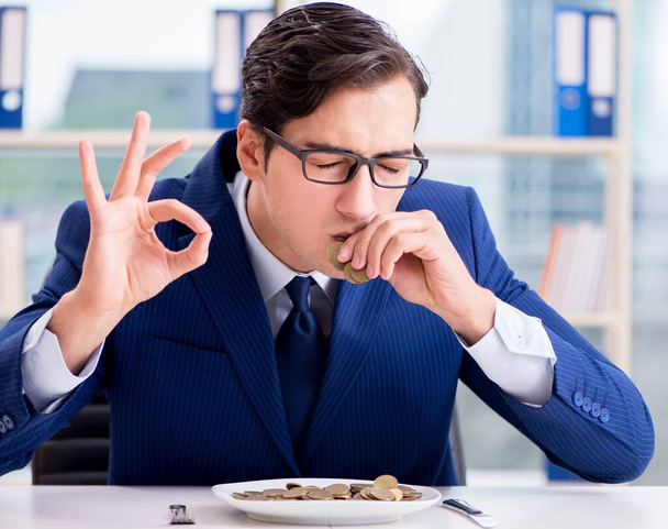 Lustiger Geschäftsmann isst Goldmünzen im Büro - Foto, Bild
