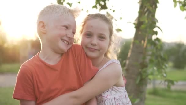 zbliżenie słodkie blondynka chłopiec pierwszy całuje jego dziewczyna w policzek w w zachód słońca - Materiał filmowy, wideo