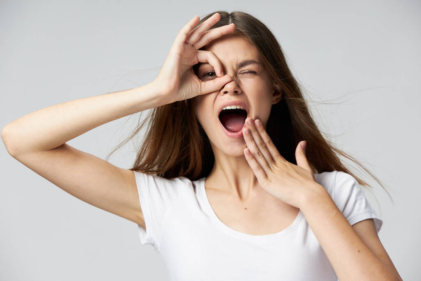 Веселая женщина с открытым ртом держит руку возле глаз эмоции белая футболка  - Фото, изображение