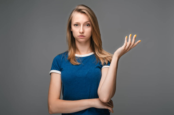 What the hell are you talking about, nonsense. Studio shot of frustrated female with blonde straight hair gesturing with raised palm, frowning, being displeased and confused with dumb question - Foto, imagen