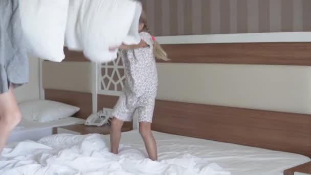 Frère et sœur jouent dans un oreiller de combat à la maison sur le lit des parents - Séquence, vidéo